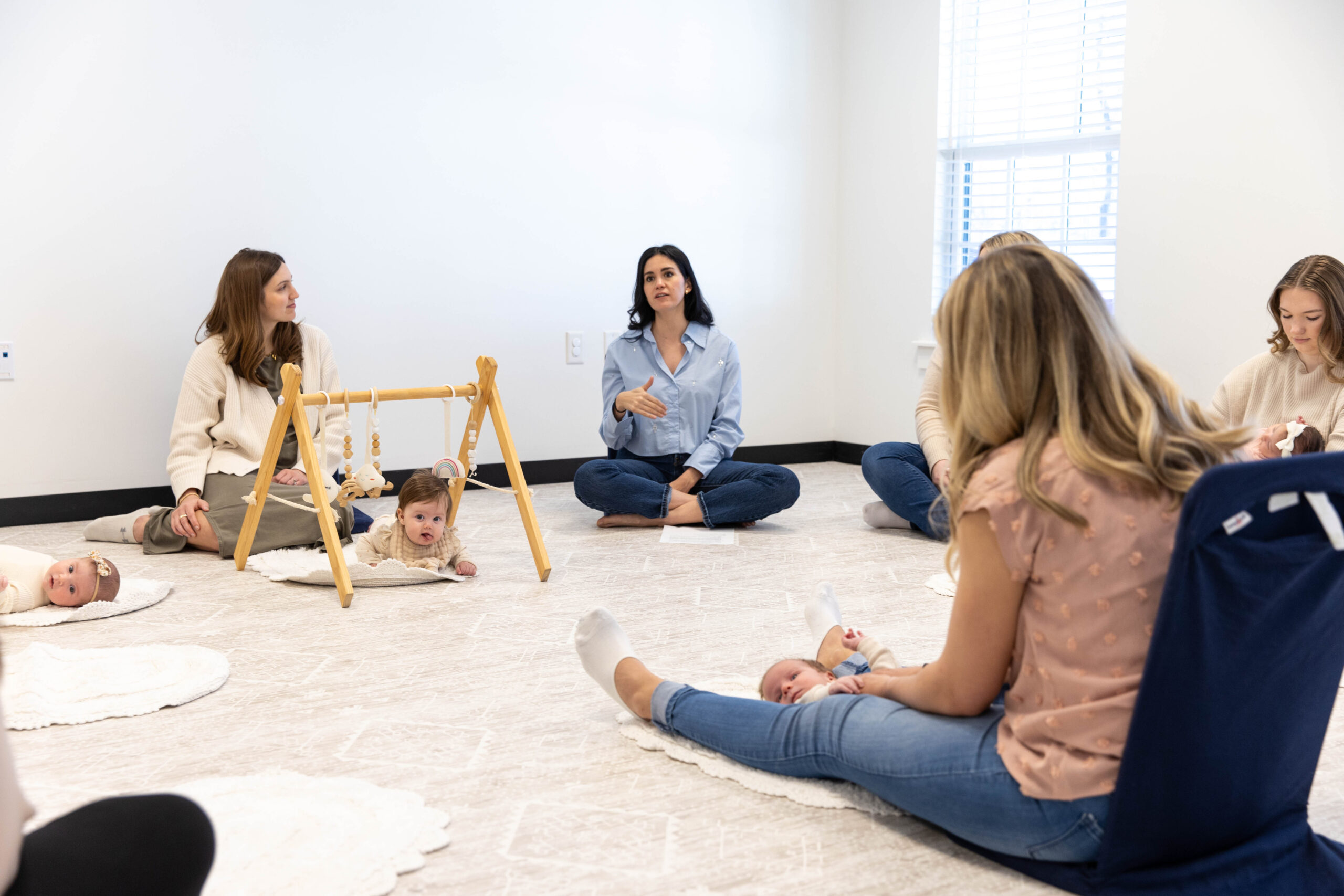 Postpartum support class in session at Hello Motherhood in Franklin, with a facilitator leading a discussion and moms engaging in conversation.